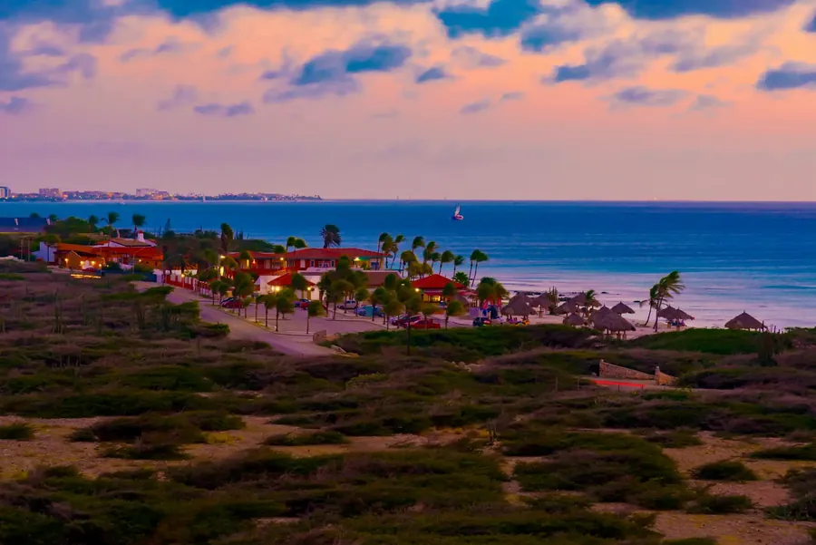 La costa de Aruba al atardecer con una playa larga y agua turquesa