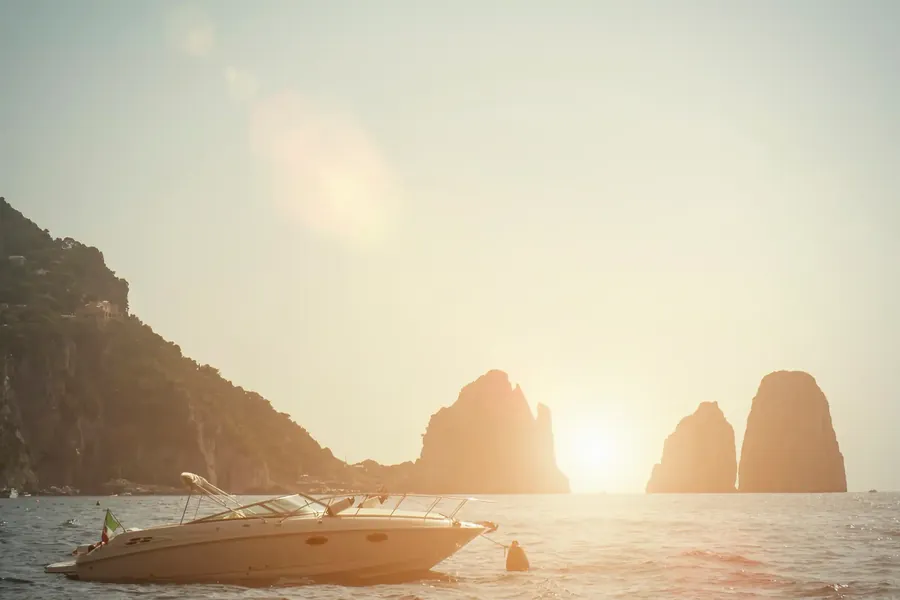 Los Faraglioni de Capri al atardecer con un barco pasando
