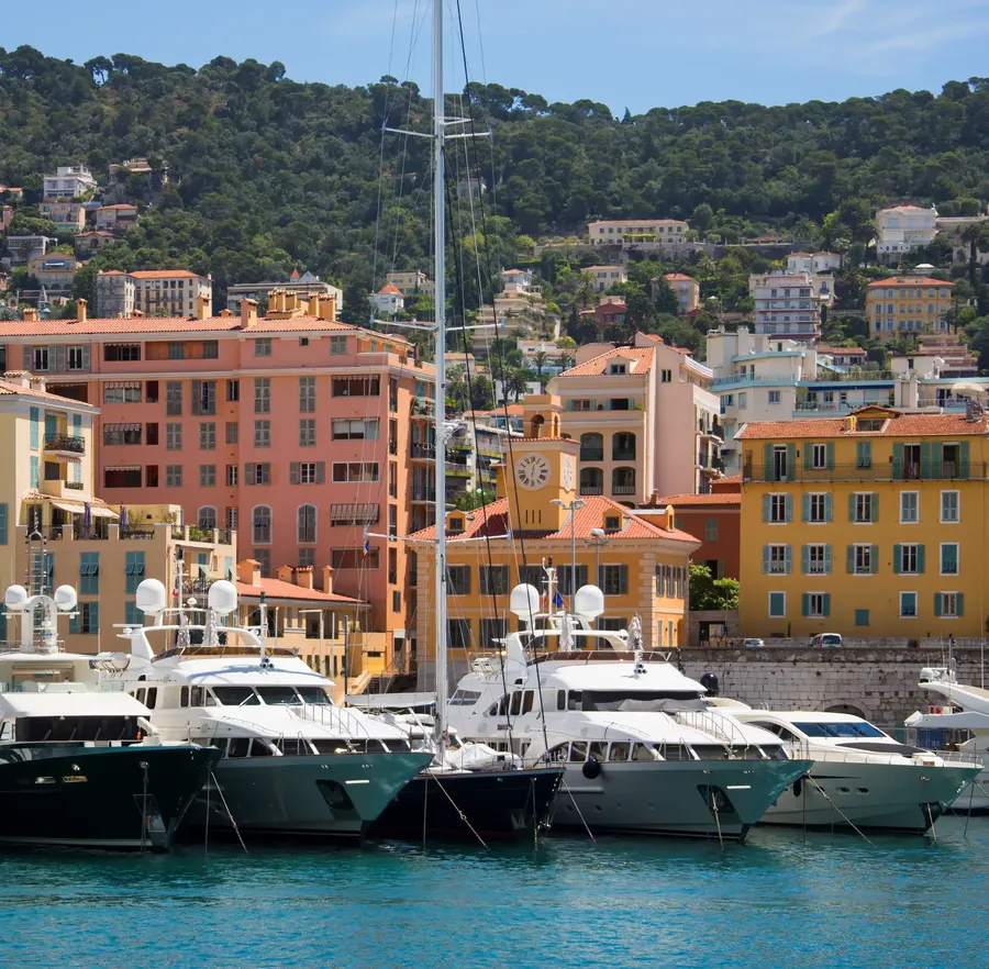 El puerto viejo de Niza con casas ocre, barcos y colinas detrás