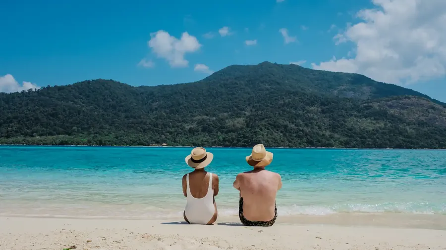 Koh Lipe con agua turquesa, una barca de cola larga y una isla verde detrás