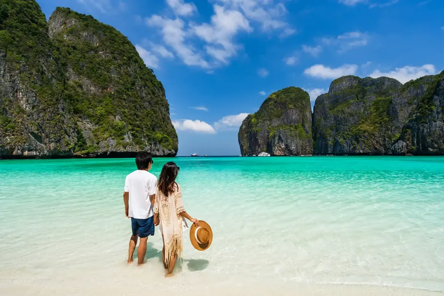Una pareja en una playa blanca entre acantilados de caliza