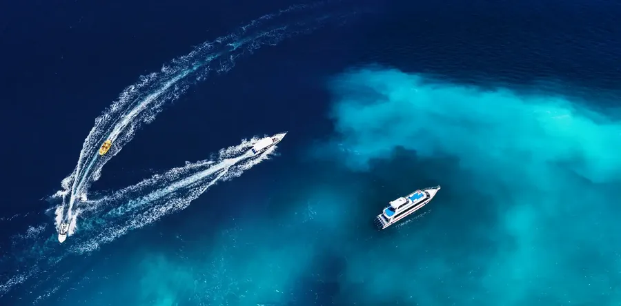 Lanchas cruzando un mar azul profundo cerca de Bali, vistas desde arriba