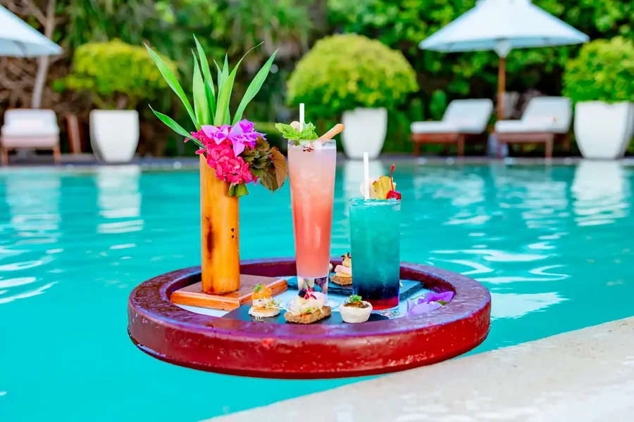 Cócteles en una bandeja flotante en una piscina tropical