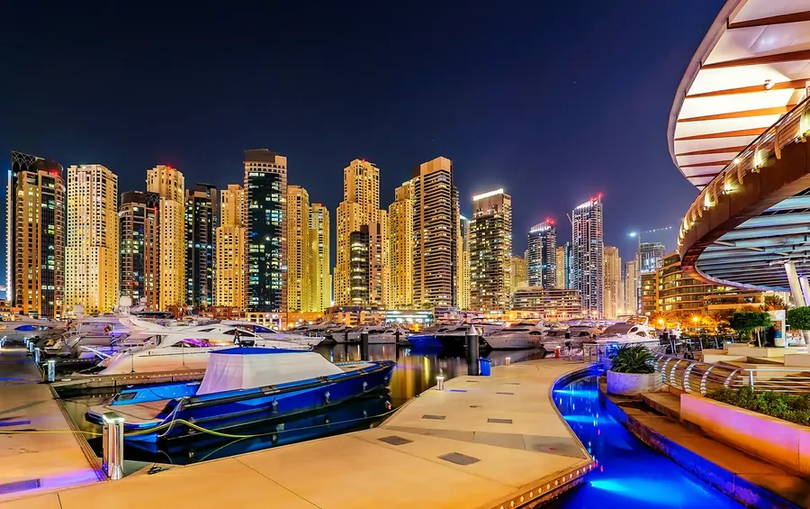 Dubai Marina de noche con rascacielos iluminados y yates