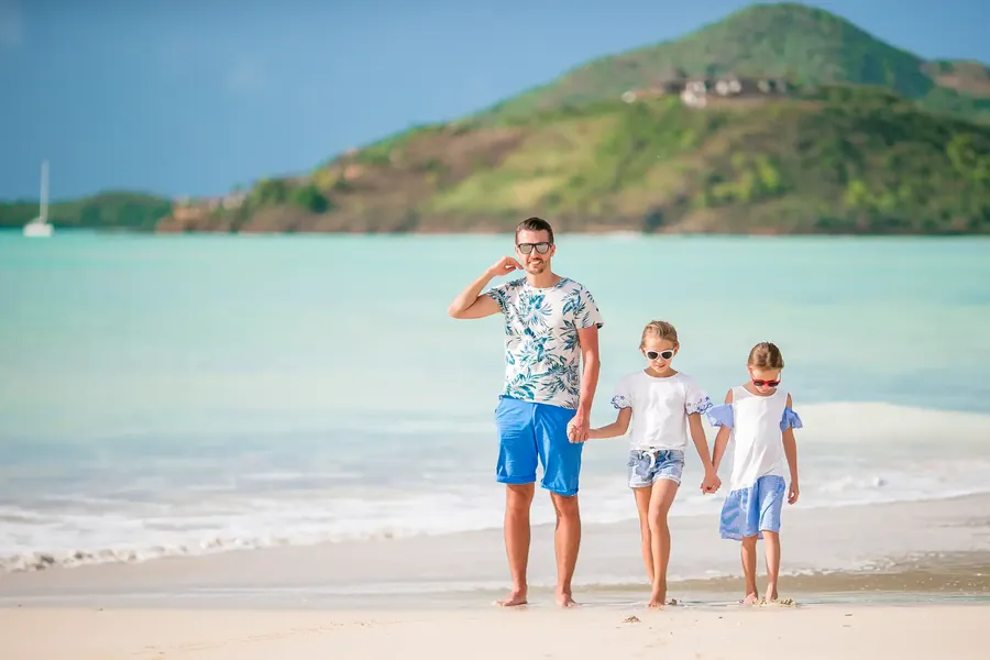 Un padre pasea por la playa con sus dos hijas